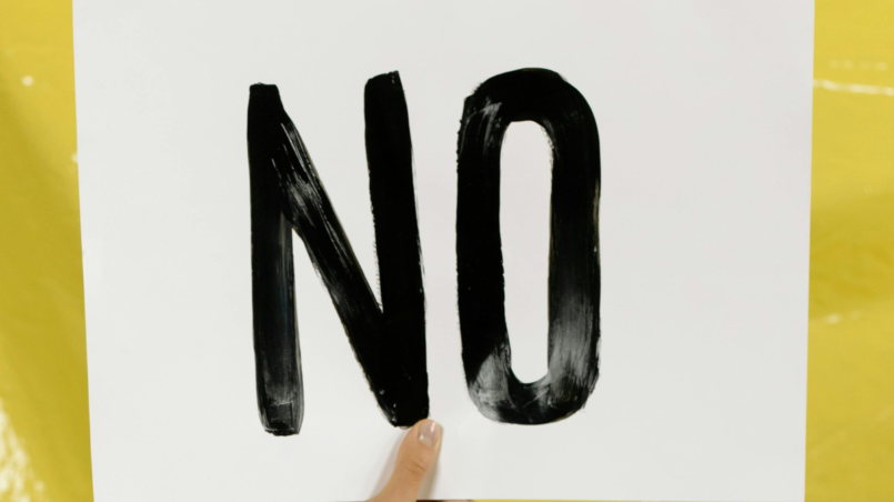 Hand holding a poster that says 'NO.'